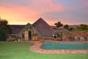 a house with a thatched roof and a swimming pool at Mokoya Lodge in Hekpoort