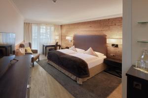 a hotel room with a large bed and a desk at Das Alpenhaus Kaprun inkl Zell am See-Kaprun Sommerkarte in Kaprun
