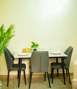 a dining room table with chairs and a white wall at Chuma's home in Arusha +3 photos