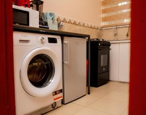 a washing machine in a kitchen with a microwave at Chuma's home in Arusha