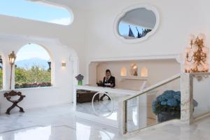 a woman sitting at a desk in a white room at Grand Hotel de la Ville in Sorrento +67 photos