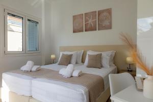 a white bedroom with two towels on a bed at Mia's Studio in Corfu