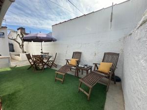 a patio with chairs and tables and an umbrella at Refúgio Alentejano in Estremoz