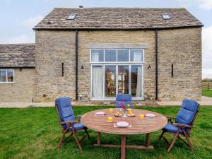 a wooden table with four chairs in front of a house at 2 Bed in Lechlade oc-77493 in Langford