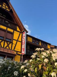 a yellow building with a sign in front of it at Hotel Restaurant Au Parc des Cigognes in Kintzheim