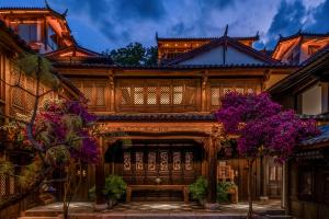 an old house with purple flowers in front of it at Maison lyly 300 Year Historical Cultural Courtyard and Ancient City View in Lijiang