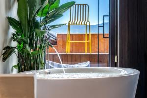 a bath tub sitting in front of a window with a chair at Maison lyly 300 Year Historical Cultural Courtyard and Ancient City View in Lijiang