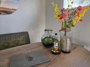 a wooden table with flowers and bottles on it at Natuurhuisje Hellendoorn in Haarle +24 photos