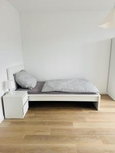 a bed in a room with a white wall at Siegen Apartments - Modern & mit Parkplatz in Siegen