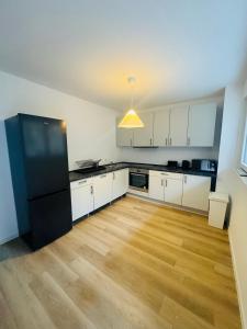 a kitchen with white cabinets and a black refrigerator at Siegen Apartments - Modern & mit Parkplatz in Siegen