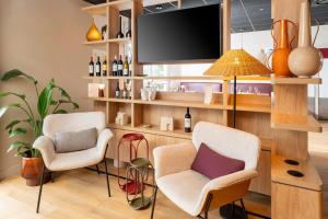 a living room with two chairs and a flat screen tv at Best Western Hôtel du Phare in Mérignac