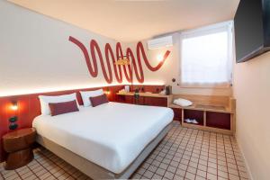 a large white bed in a room with a sign on the wall at Best Western Hôtel du Phare in Mérignac