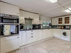 a kitchen with white cabinets and a washer and dryer at 2 Bed in Romsey oc-thatc in Newtown