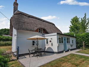 a cottage with a table and chairs and an umbrella at 2 Bed in Romsey oc-thatc in Newtown