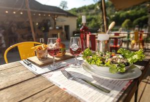a table with a plate of salad and wine glasses at Glamping Saint Germain in Saint-Germain-du-Bel-Air