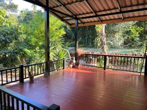 a wooden deck with a view of a forest at Ban Suan Chana Homestay in Ban Pha Saeng Lang