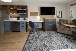 a living room with a couch and a chair and a kitchen at Candlewood Williamsport by IHG in Williamsport