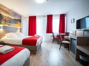 a hotel room with two beds and a desk at Hotel Restaurant Au Parc des Cigognes in Kintzheim