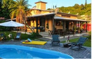 a house with a swimming pool in front of a house at Pousada bella mar buzios in Búzios
