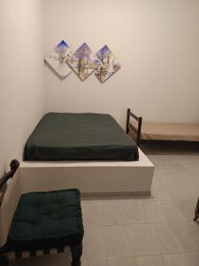 a bedroom with a bed with two paintings on the wall at Chácara braga in Itanhaém