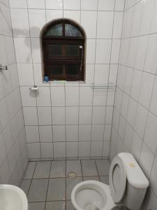 a bathroom with a toilet and a window at Chácara braga in Itanhaém +18 photos