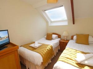 two beds in a room with a tv and a window at 3 Bed in Bamburgh oc-cn222 in Warenford +7 photos