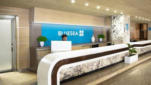 a woman sitting at a desk in a lobby at BLUESEA Copacabana in Lloret de Mar