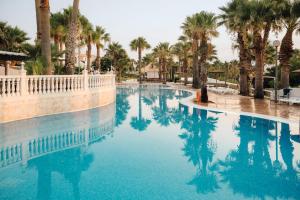 a swimming pool with palm trees and blue water at BLUESEA Marina Parc in Na Macaret