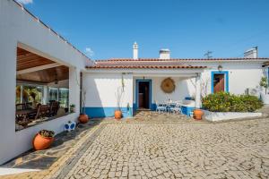 a white house with a cobblestone patio in front of it at Monte da Pechincha - Casa de Hóspedes & Spa in Estremoz
