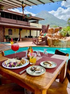 a table with plates of food and drinks on it at Hotel La Pradera del Arenal in Fortuna