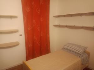 a small bed in a room with red curtains at Corte Don Bosco 4 in Monfalcone