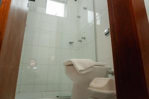 a white bathroom with a shower and a toilet at Hotel Canaan in Sete Lagoas +35 photos