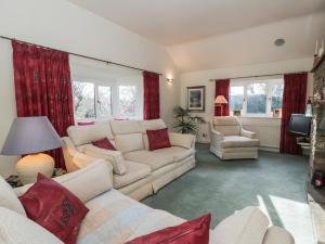 a living room with white furniture and red curtains at Summerhill in Hereford
