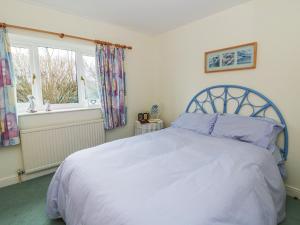 a bedroom with a white bed with a blue headboard and a window at Summerhill in Hereford