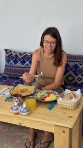 a woman sitting at a table with plates of food at Blue Tizirin House in Tamraght Ouzdar +12 photos