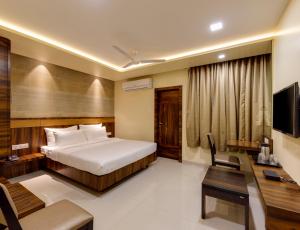 a bedroom with a bed and a desk and a television at Hotel Silver Oak 7 Minutes Walk to Mahalaxmi Temple in Kolhapur