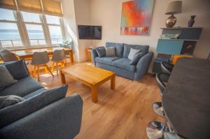 a living room with blue couches and a table at Oceanview in Woolacombe