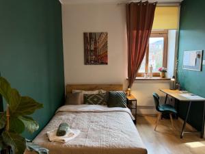 a bedroom with a bed and a desk and a window at Pod Aniołami in Wałbrzych