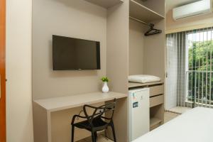 a room with a desk and a tv on a wall at Hotel Canaan in Sete Lagoas