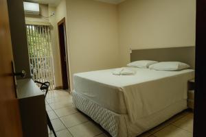 a bedroom with a white bed and a balcony at Hotel Canaan in Sete Lagoas