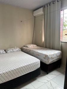 two twin beds in a room with a window at Perfeita casa estilo apartamento in São Luís