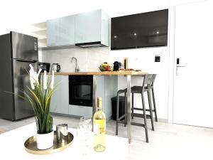 a kitchen with stainless steel appliances and a table with a bottle of wine at Central Suites Aegina 3 in Egina