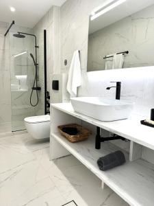 a white bathroom with a sink and a toilet at Central Suites Aegina 3 in Egina +45 photos
