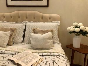 a bed with an open book and a vase of flowers at Chalé do Vale à 10 min de carro de Itacoatiara in Niterói