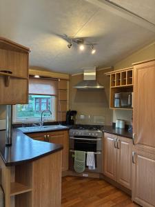 a kitchen with wooden cabinets and a stove top oven at The Grosvenor 45 in Ardentinny
