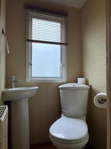 a bathroom with a toilet and a sink and a window at The Grosvenor 45 in Ardentinny +4 photos