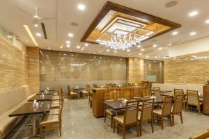 a restaurant with tables and chairs and a chandelier at Hotel Silver Oak 7 Minutes Walk to Mahalaxmi Temple in Kolhapur