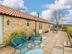 a patio with two blue chairs and a building at 2 Bed in York oc-91540 in Brandsby
