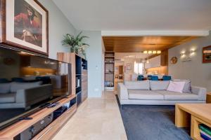 a living room with a couch and a tv at Vista Laguna - Harbour View - Private Jacuzzi in Għajnsielem