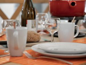 a table with a plate and wine glasses on it at Chalet Banksia by Interhome in Ovronnaz
